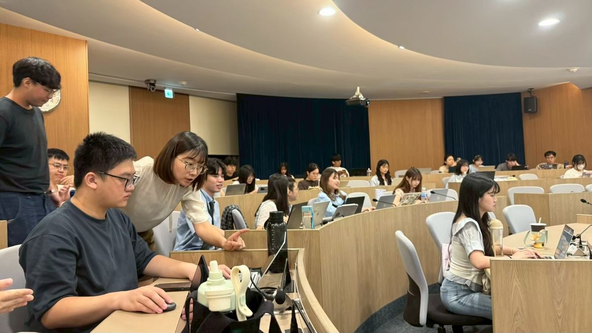 2026 年 5 月政大工作坊，講師俯身在座位旁協助學員操作
